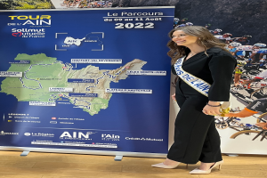 Eine Frau steht vor einer Fahne mit einer Frankreich-Karte, trägt ein Band mit der Aufschrift "Tour de France 2020."