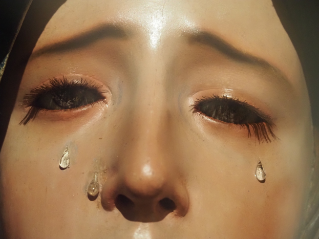 Eine Frau mit Tränen auf den Wangen, ihr Gesichtsausdruck öffnet Trauer und Verzweiflung.