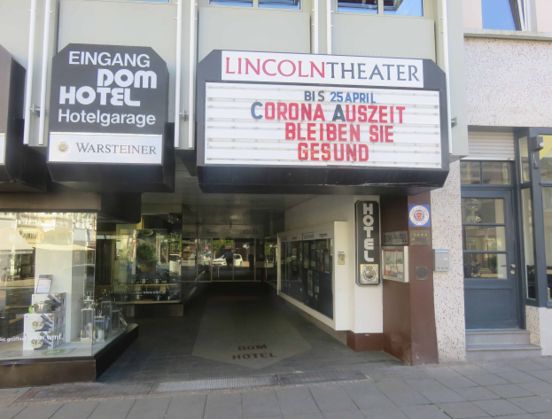 Außenansicht des Lincoln Theaters in Berlin, Deutschland, mit Glasfenstern und -türen, einem Schild und einem Blick ins Innere, der eine belebte städtische Umgebung vermuten lässt.