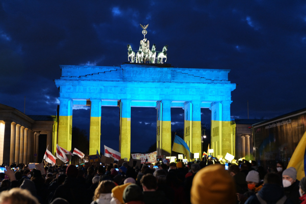 Eine Menschenmenge steht vor dem Brandenburger Tor in Berlin, Deutschland, mit Fahnen und Plakaten, auf denen ein Banner auf der rechten Seite des Bildes zu sehen ist.