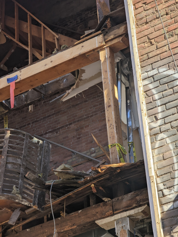 Ein teilweise abgerissenes Gebäude mit verstreuten Holzplanken und Trümmern, das gebrochene Fenster und Türen aufweist.