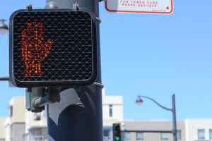 Eine Straßenszene in einer Stadt mit Verkehrspfählen, Ampeln, Straßenlaternen, Gebäuden und einem klaren Himmel.