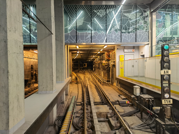 Eine Londoner U-Bahn-Haltestelle bei Nacht mit einem Zug auf den Schienen, beleuchtet von Deckenlampen, einer Plattform und Säulen auf der linken Seite und einem Signal mit einem Pfahl auf der rechten Seite.