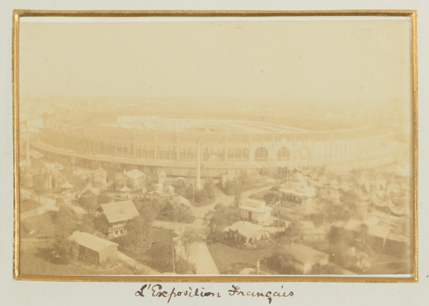 Altes Schwarz-Weiß-Foto eines Stadions inmitten einer Stadtlandschaft mit umliegenden Gebäuden, Bäumen und Strommasten sowie unten sichtbarem Text.