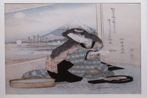 Eine Frau in einem Kimono sitzt auf dem Boden vor einem Berg, umgeben von einem Foto Rahmen mit Text, mit Booten auf dem Wasser, Hügeln und einem bewölkten Himmel im Hintergrund.