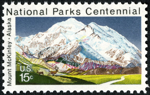 Postage stamp with "National Parks Centennial" text and a mountain range in the background.