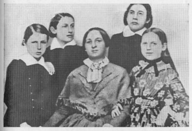 Schwarzes und weißes Foto einer vielfältigen Gruppe von Frauen, mit einer sitzenden in der Mitte, und dem Text "Die Frauenwahlrechtsbewegung" unten.