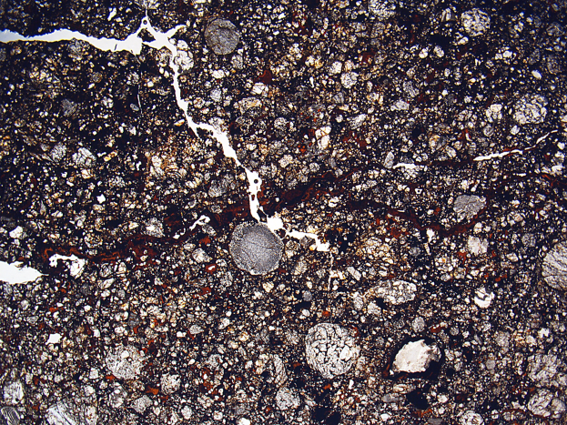 Nahaufnahme einer gesprungenen, schmutzigen Straße mit rauer, unebener Oberfläche.