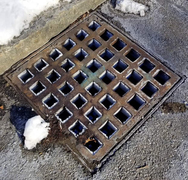 Eine Metall-Schachtobjekt auf der Seite einer Straße, umgeben von Schnee.