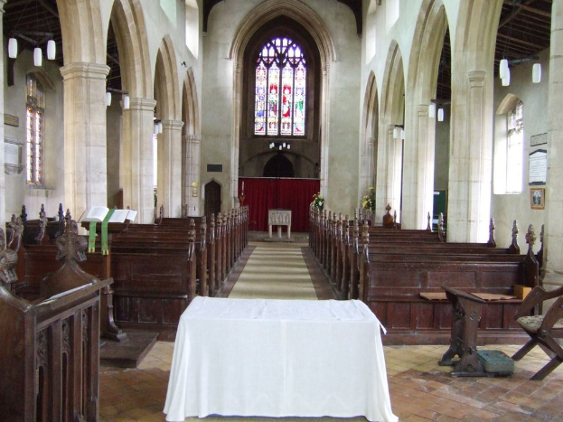 Ein Raum mit Tischen, einem Podium, einem Buchständer, Stühlen, Bänken, Säulen, Tafeln, einem Vorhang, Fenstern, Stoff, Pflanzen und verschiedenen Gegenständen.