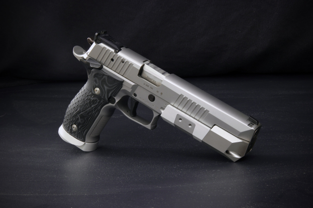 Eine Sig Sauer P226 X-Five 9mm Pistole auf einer schwarzen Oberfläche mit schwarzem Hintergrund.