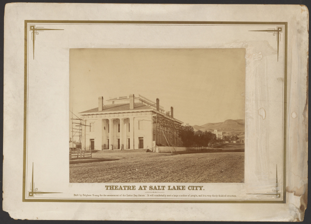 Schwarzes und weißes Foto des Theaters in Salt Lake City, mit einem zentralen Gebäude, das von Bäumen und Hügeln umgeben ist, und Text unten.