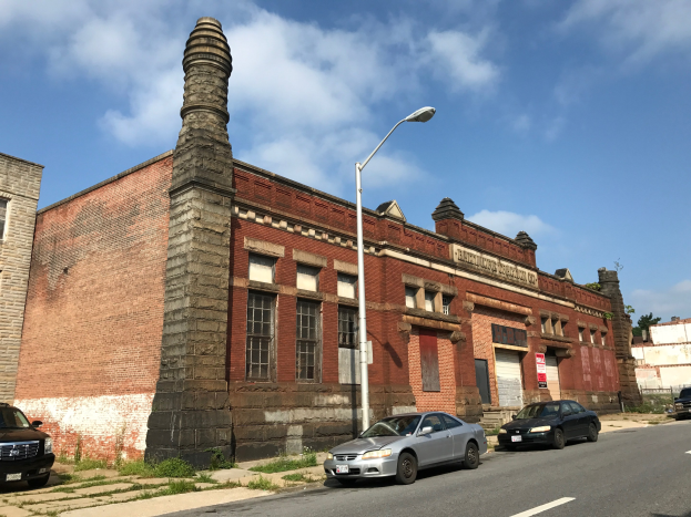 Alter Backsteinbau mit seitlichem Schornstein, als ehemalige St. Louis Feuerwache bezeichnet, umgeben von Straßenmasten, Laternen, Fahrzeugen, Schildern, Bäumen und einem bewölkten Himmel.