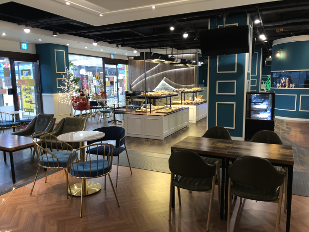 Restaurant-Innenraum mit Tischen, Stühlen und einem Teppichboden, mit Deckenleuchten, einem Schrank mit Gegenständen und einem Anzeigebildschirm, im Mall of America.