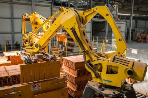 Industrielles Lager mit gestapelten Kisten, Kränen, Zäunen, Pfählen und einer fernen Wand in einer Fertigungsumgebung.