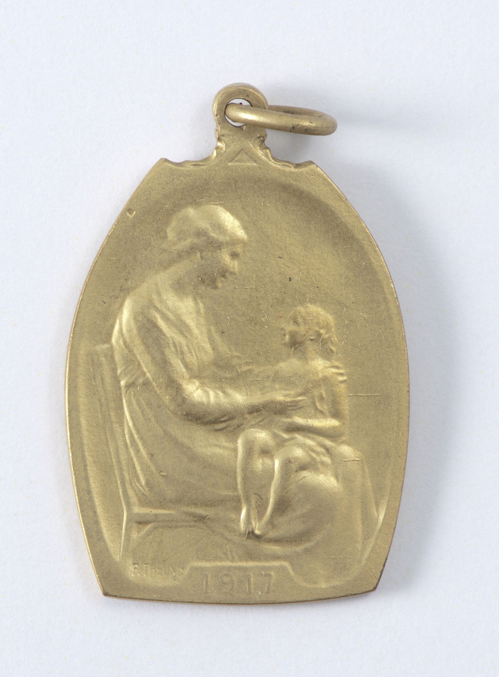 Goldmedaille mit einer Gravur einer Frau in einem weißen Kleid mit einem Dutt, die ein Kind hält, beide schauen sich gegenseitig mit Ausdrucken von Zärtlichkeit und Verwunderung an, beschriftet mit "Mutter und Kind."