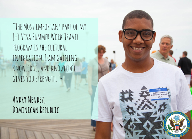 Ein Mensch in einem weißen T-Shirt lächelt umgeben von einer Gruppe, die auf einer hölzernen Oberfläche geht, mit einem Zitat von Andry Mendez über kulturelle Integration und Wissen auf der linken Seite und Gebäuden und einem klaren blauen Himmel im Hintergrund.