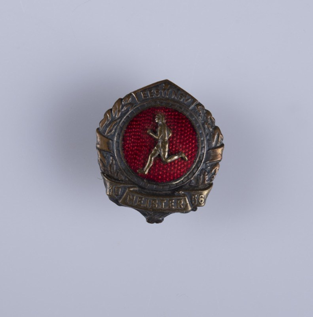 Ein rotes und goldenes Abzeichen mit einem laufenden Mann, wahrscheinlich vom 16. Infanterie-Regiment, mit einer Inschrift.