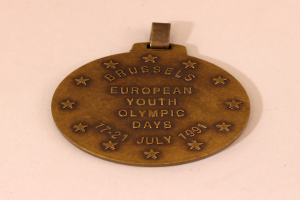 Eine Bronzemedaille mit der Inschrift "Europäische Jugend-Olympiade" auf einem weißen Hintergrund.