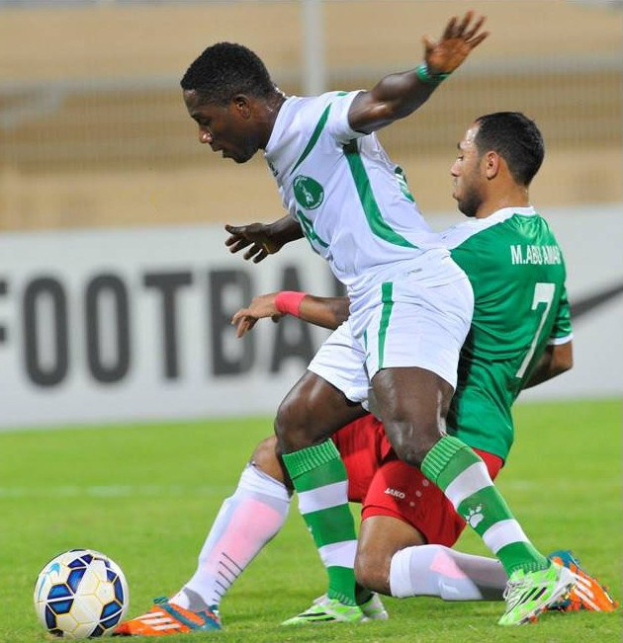 Zwei Männer spielen Fußball auf einem grünen Feld mit einem unscharfen Hintergrund, der den Text "Nigeria vs Senegal - Africa Cup of Nations" zeigt.