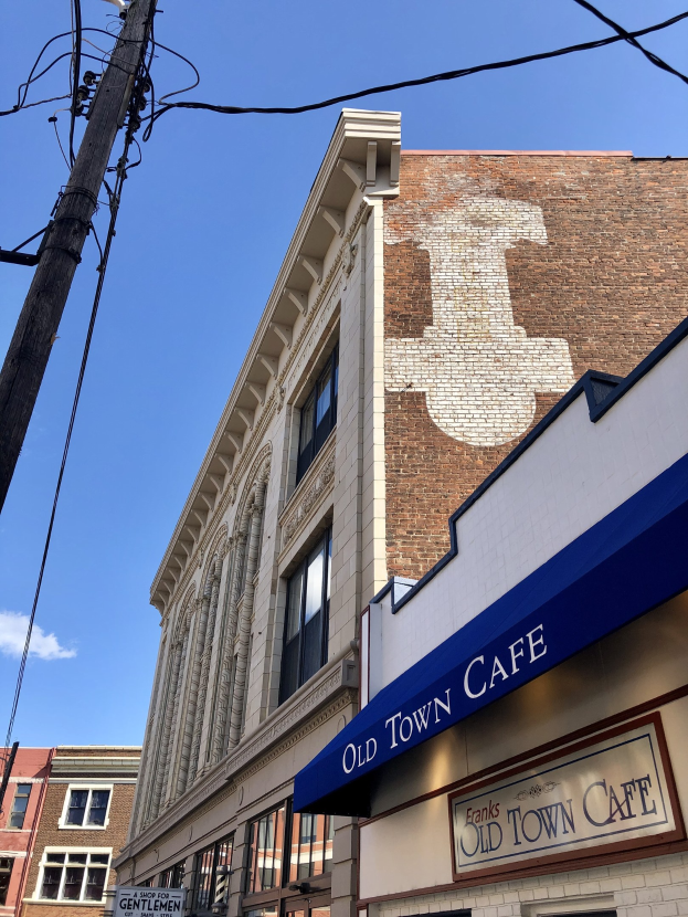Altstadt-Café an einer Straßenecke mit umliegenden Gebäuden, Beschilderung, Versorgungsmasten, Drähten und einem bewölkten Himmel.