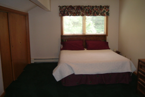 Ein Zimmer mit einem Kleiderschrank, einem Fenster und einem Bett an einer Wand.