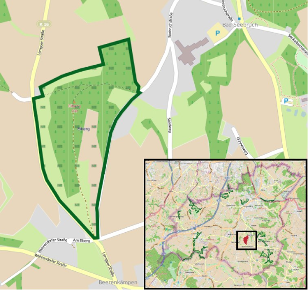 Detailierte Karte einer Stadt mit einem zentralen grünen Bereich, der für die geplante Entwicklung markiert ist, zeigt Straßen, Gebäude und Sehenswürdigkeiten.