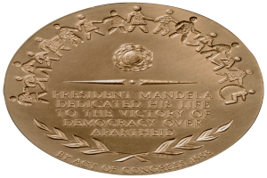 Eine Goldmedaille mit der Aufschrift "Präsident Mandela widmete sein Leben dem Sieg der Demokratie über die Apartheid" auf einem weißen Hintergrund.