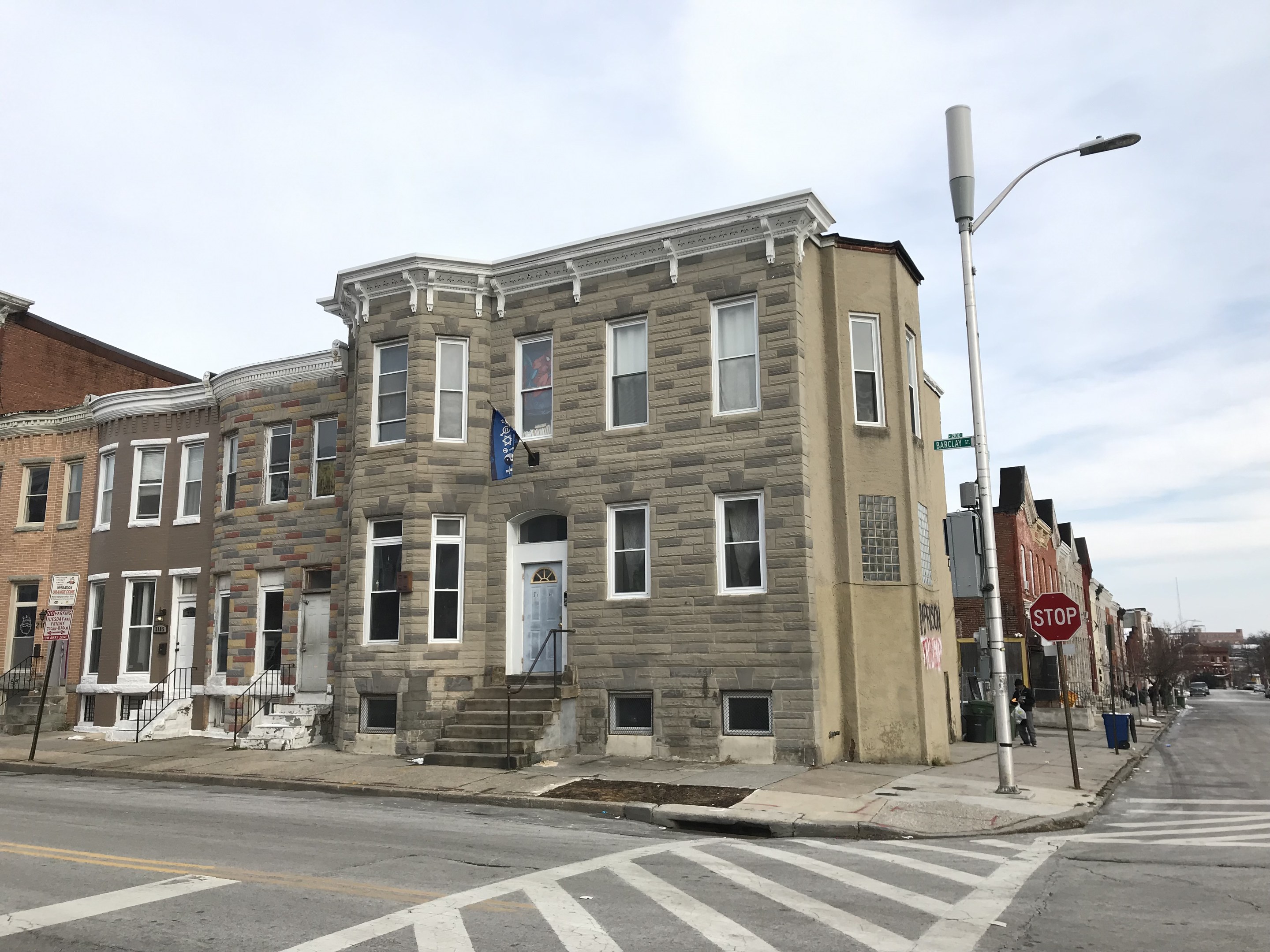 Eine Reihe von Häusern an einer Straßenecke in einem neuen Wohnprojekt in Philadelphia, mit Fahrzeugen, Bäumen und einem bewölkten Himmel im Hintergrund.
